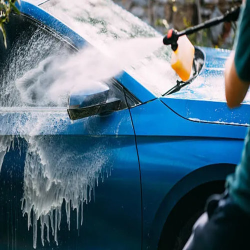 man washing car in his garden with pressure washer